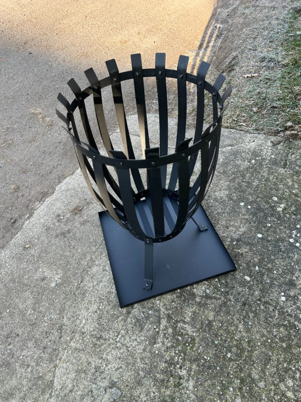 Schwarze Drahtskulptur in Form eines Korbs auf einem Gehweg.