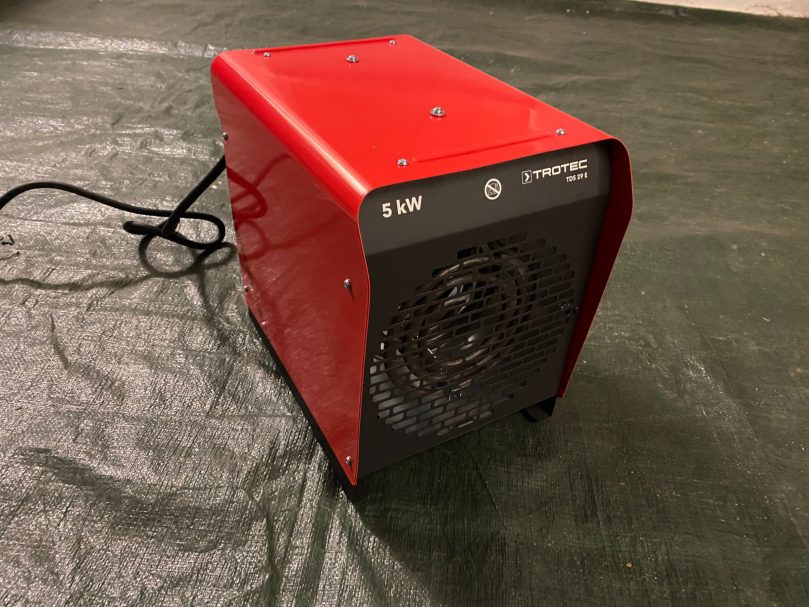 Roter elektrischer Heizlüfter mit schwarzem Frontgitter und Kabel.