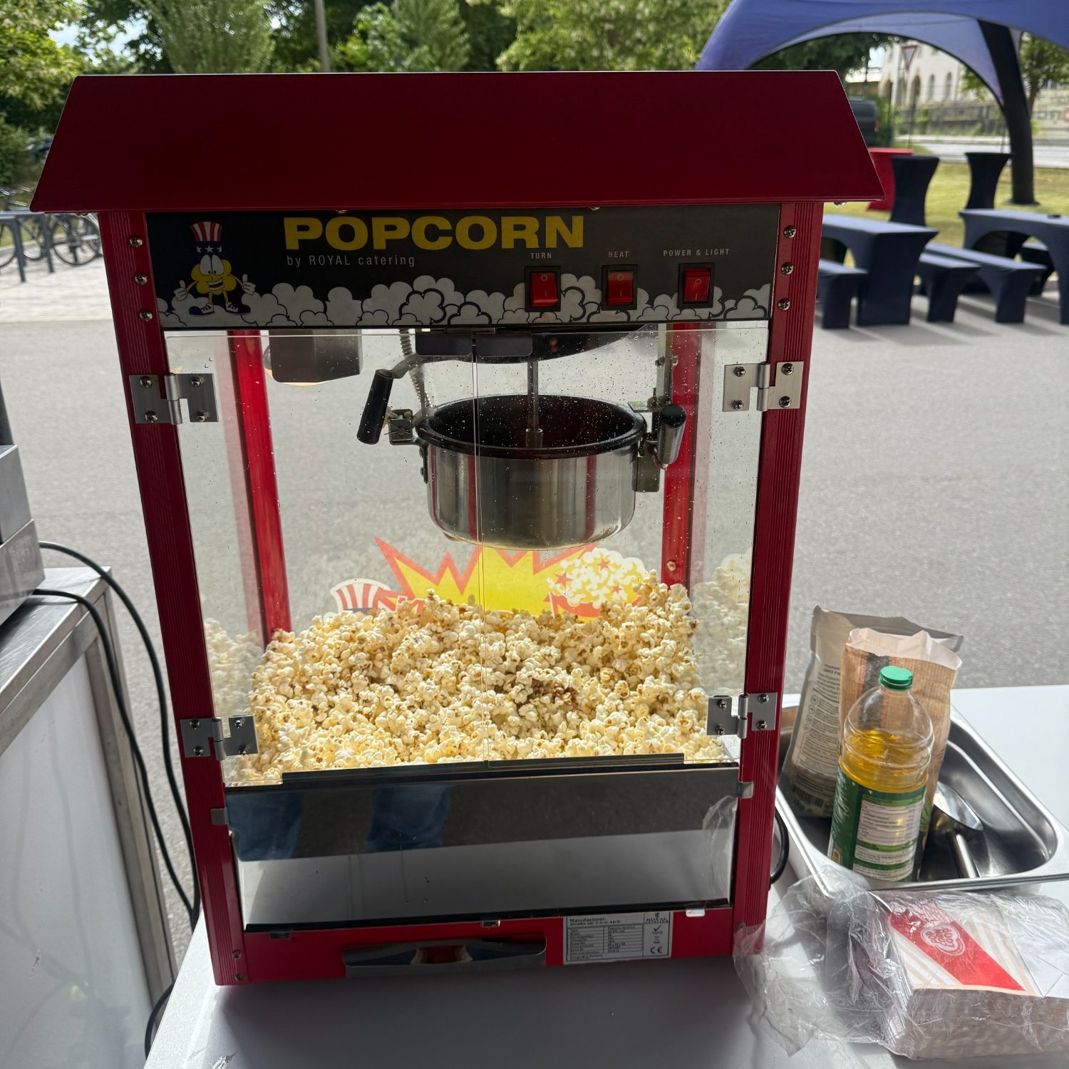 Roter Popcorn-Maker mit frischem Popcorn und Zubehör daneben.