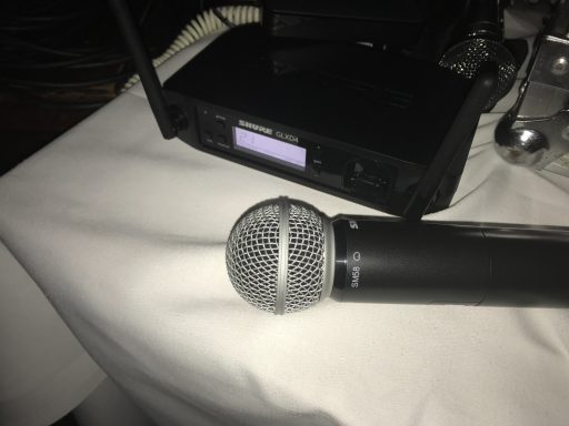 Schwarzes Mikrofon liegt auf einem Tisch neben einem Mikrofonempfänger.